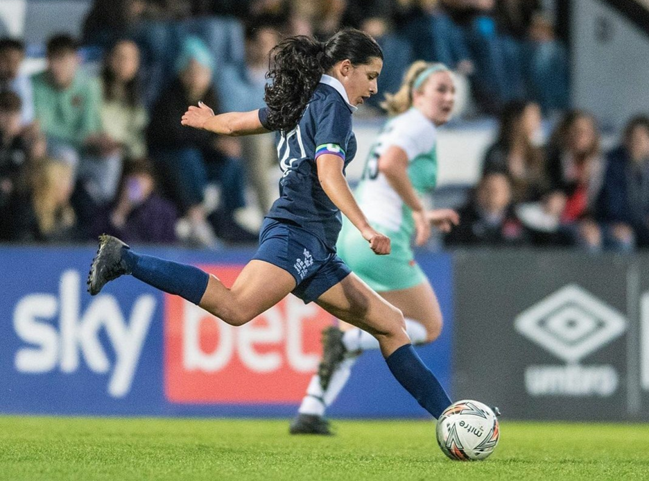 Student Iona plays football against Cambridge dressed in dark blue