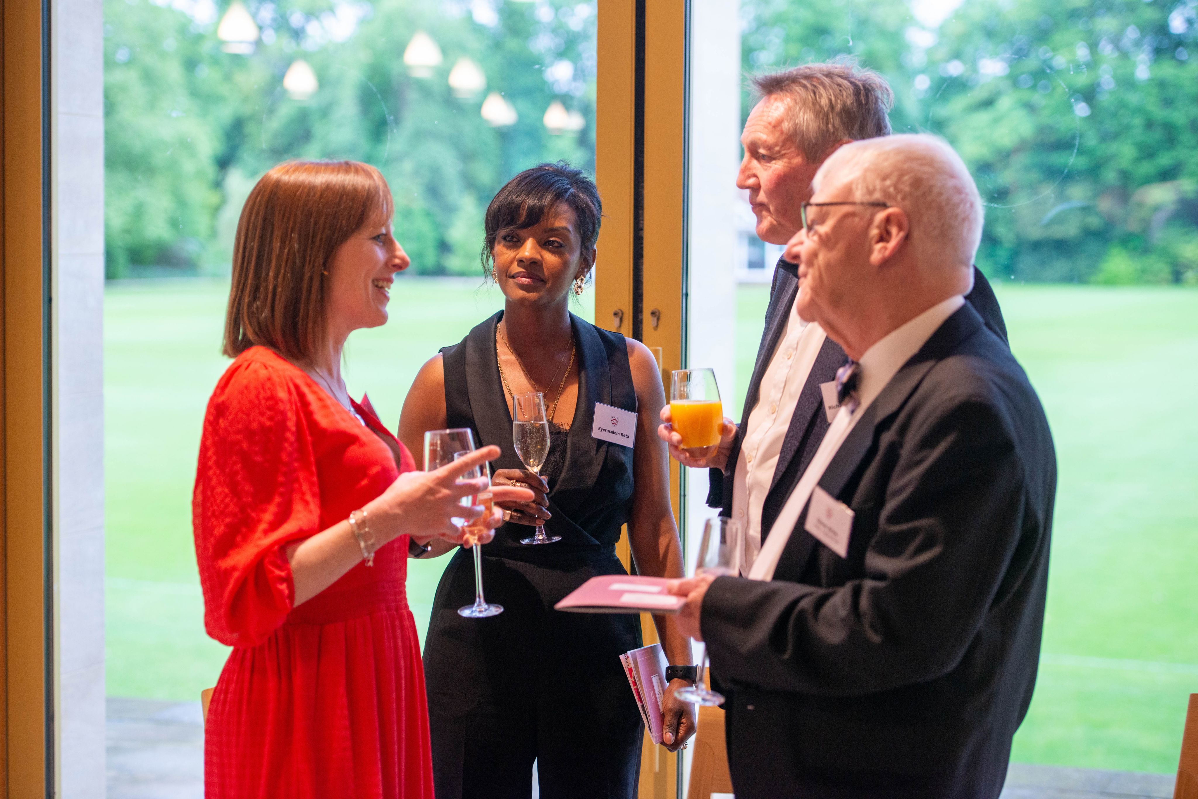 Women, Viola, dressed in orange talking to alumni