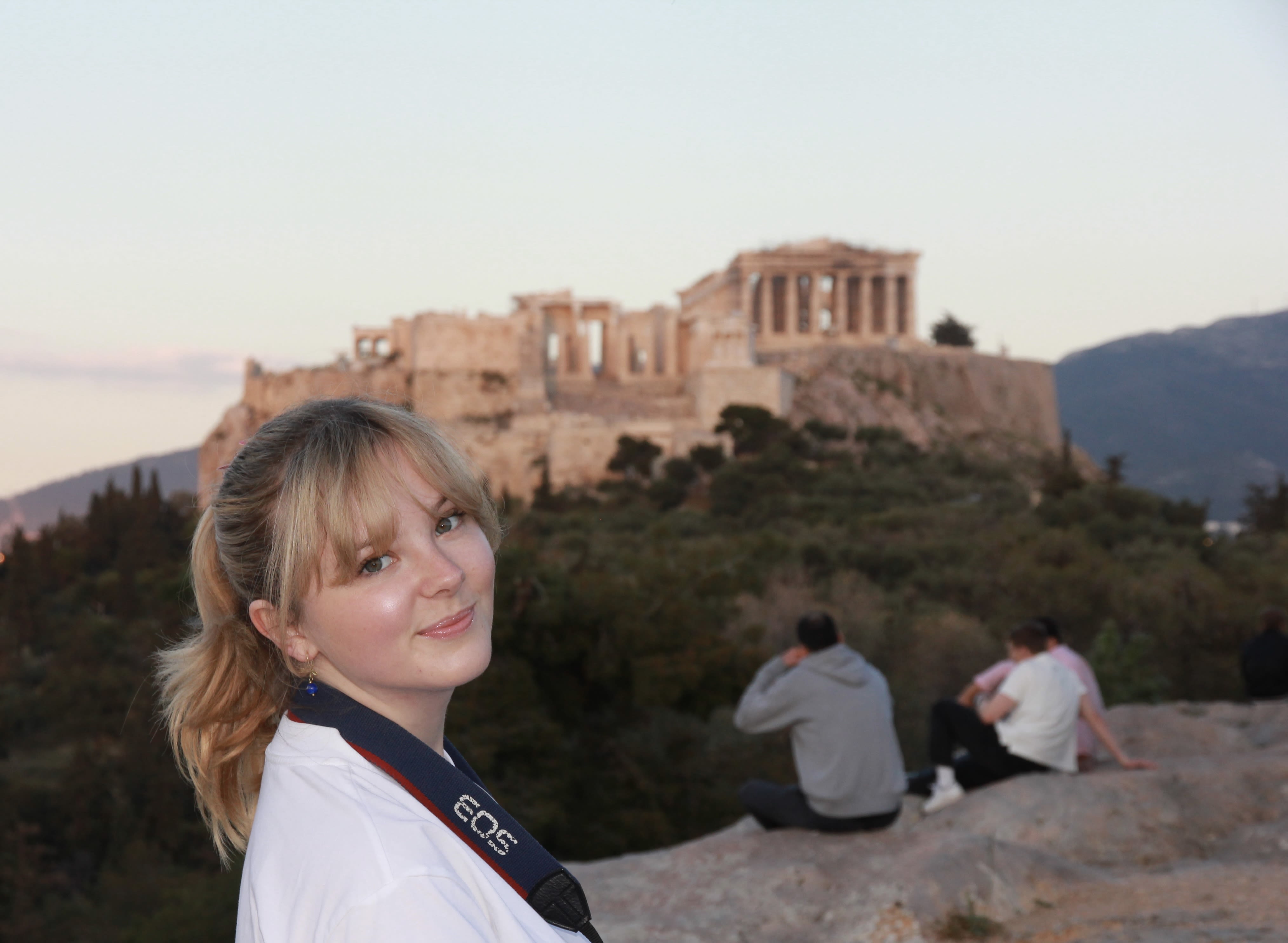 Blonde woman smiles in front of Acropolis