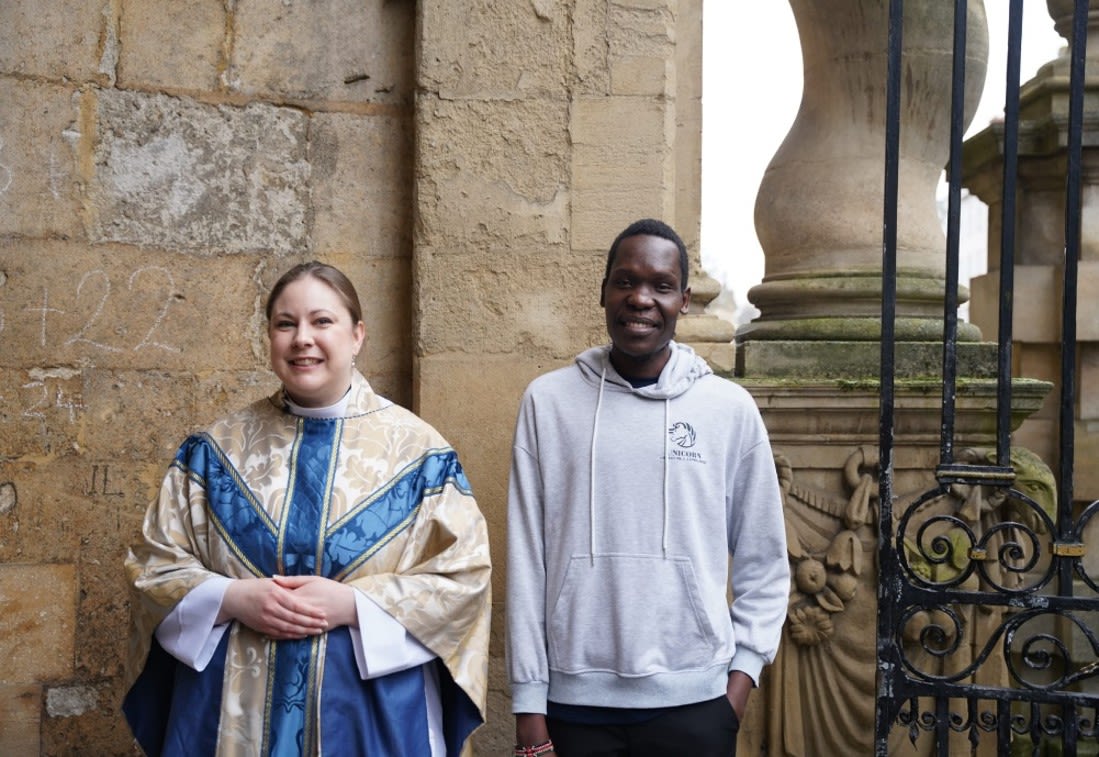 Male student next to vicar smiles at camera